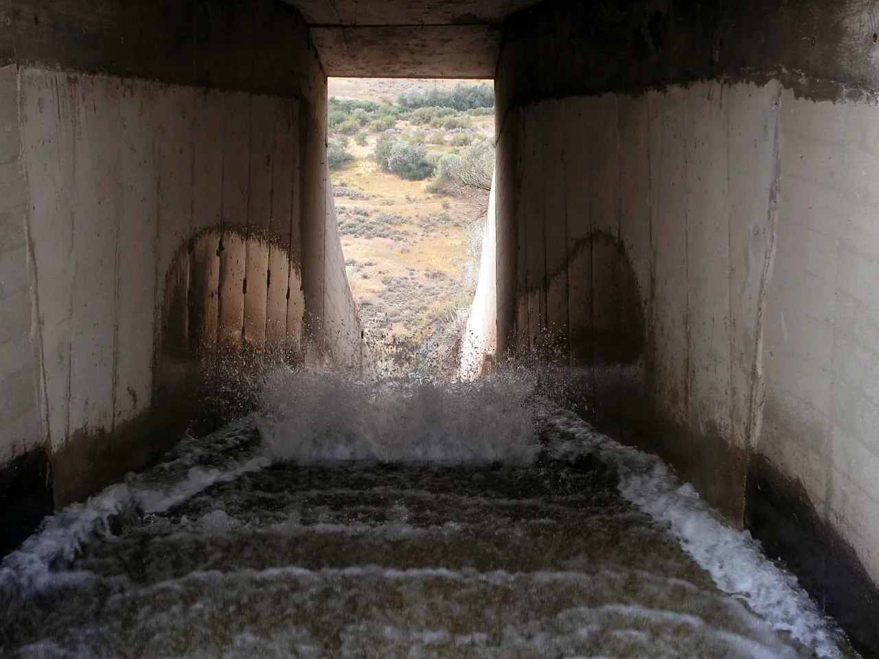 Water rushing through a concrete spillway out into the high desert